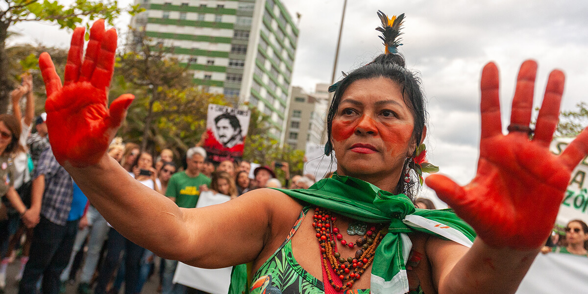 A woman holding up the palm of her hands painted in red during a demonstration.